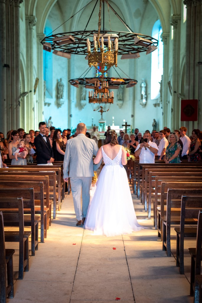une mariée en robe blanche remonte l'allée de l'église, photo de mariage